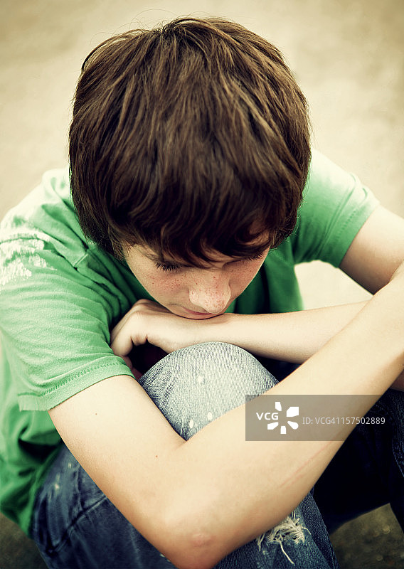 双臂交叉头靠膝盖的少年图片素材