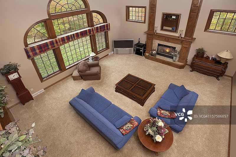 可俯瞰的大客厅，配有蓝色沙发、情侣座和壁炉图片素材