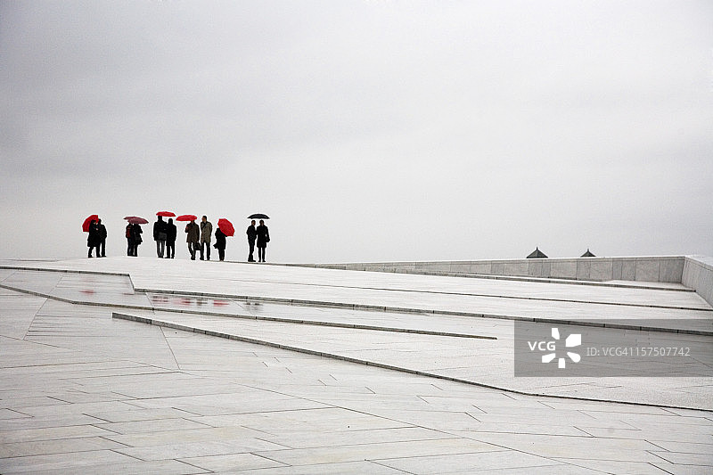 在现代鹅卵石广场上撑伞的人们图片素材