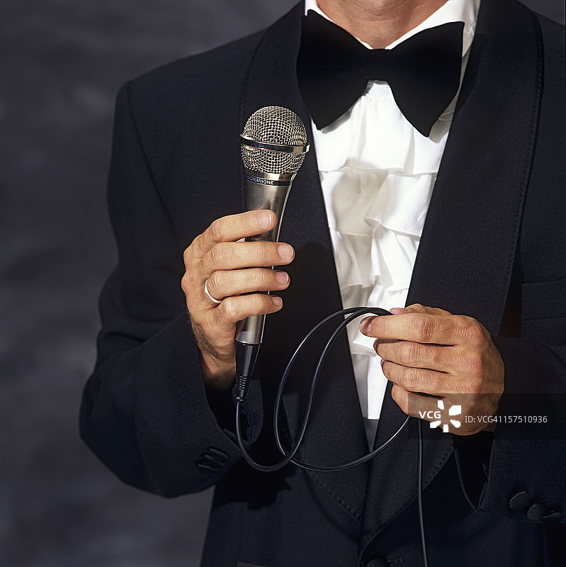 身着优雅西装的会议主持人手持麦克风图片素材