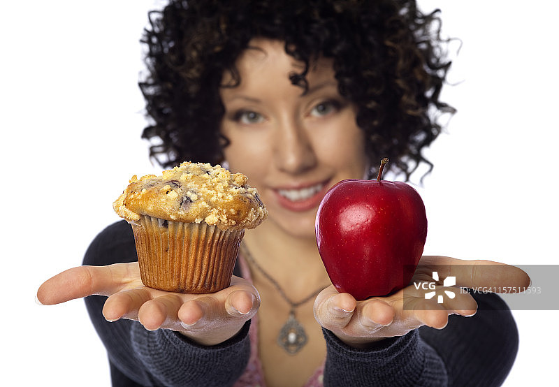 健康饮食选择：女人手拿玛芬与苹果图片素材