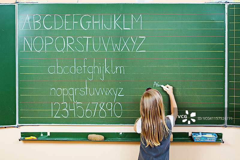 女学生在黑板上写字（后视图）图片素材