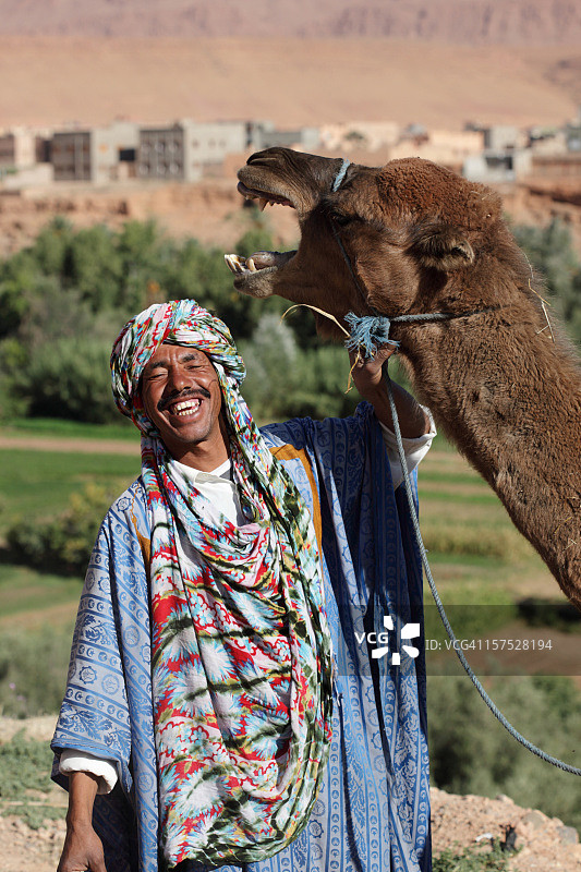 快乐的柏柏尔人和他的骆驼分享欢乐的时刻，摩洛哥图片素材