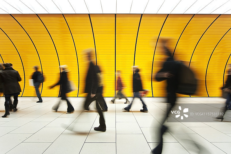 在黄色隧道走廊中模糊移动的人们图片素材