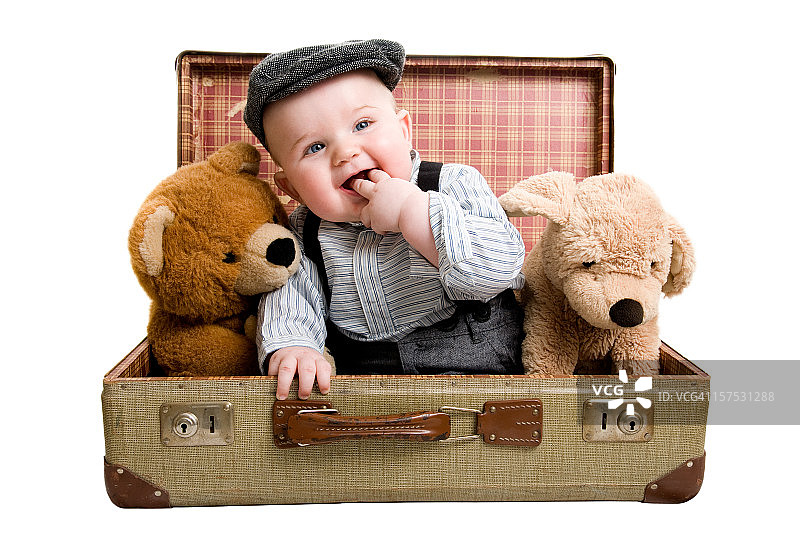 快乐的男孩和他的泰迪熊一起坐在复古手提箱里图片素材