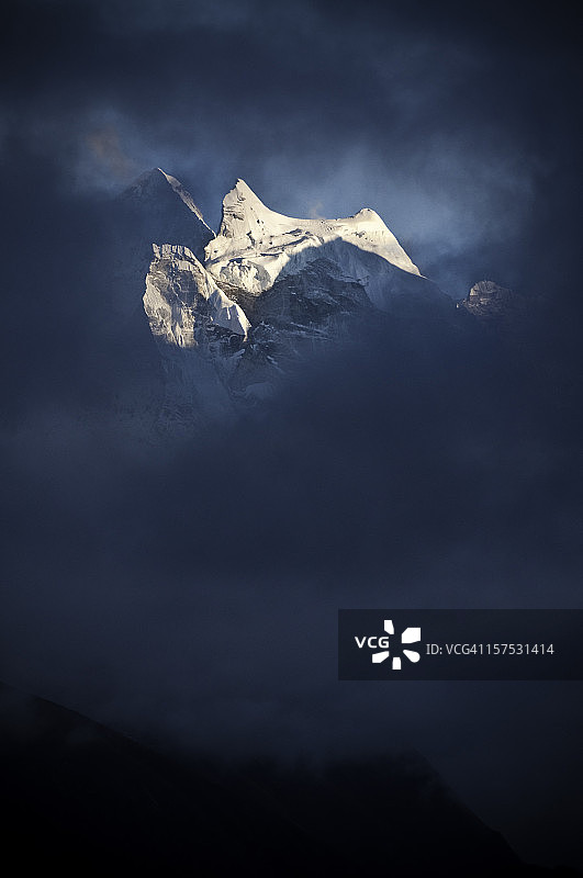 阳光下的喜马拉雅雪峰和尼泊尔昆布的黑色漩涡状风暴云图片素材