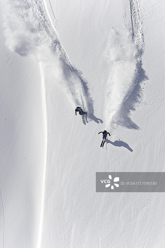 两名滑雪者在粉雪中滑下坡的航拍图片素材