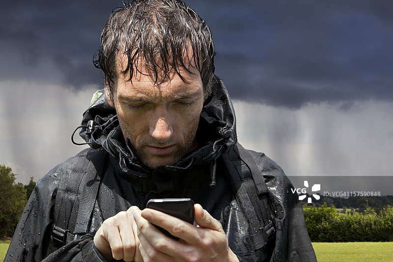 雨中徒步者使用触摸屏GPS智能手机图片素材