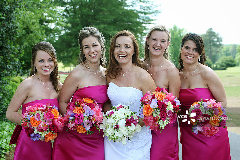 快乐的新娘被穿着粉色礼服的伴娘们簇拥着图片素材