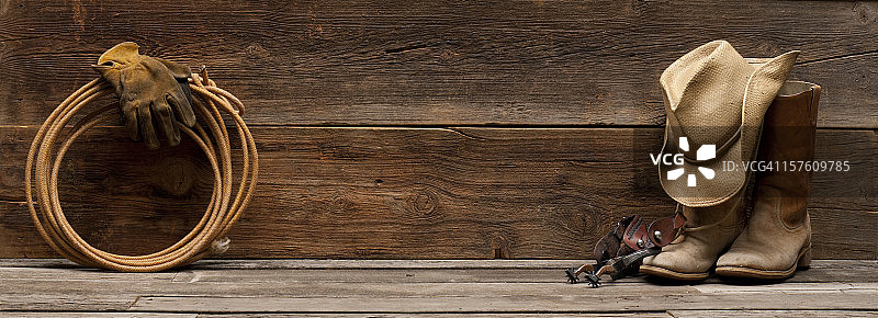 狂野西部谷仓木背景，配靴子、帽子、马刺和绳索图片素材