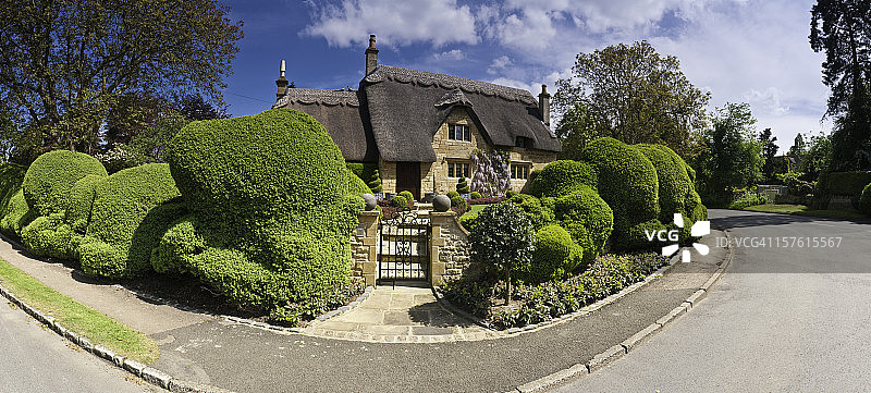 茅草小屋，翠绿的夏日花园，静谧的乡村小路全景图片素材