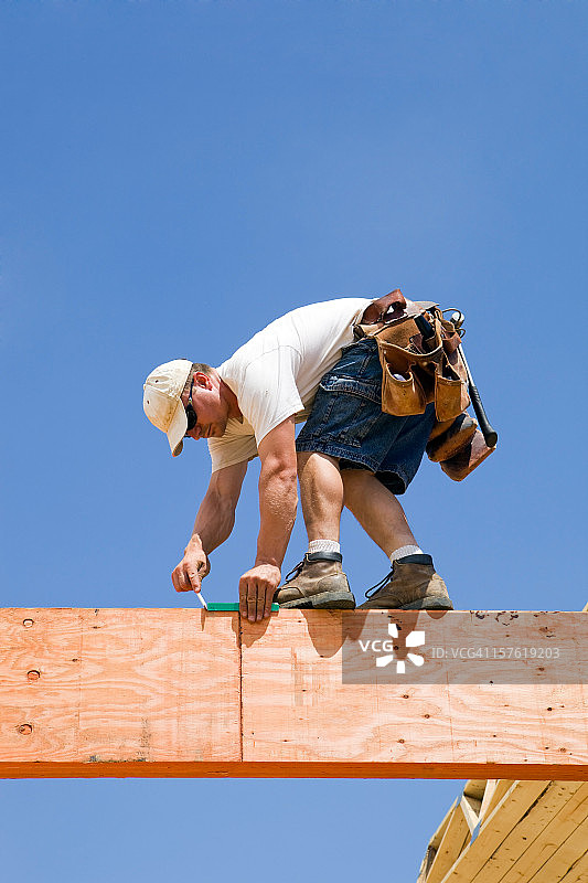 建筑工人在层压木梁上使用角尺图片素材