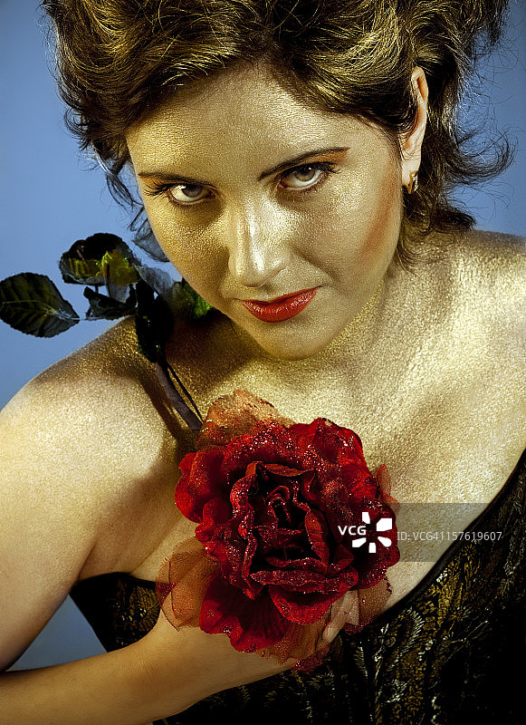 拥有金色皮肤的年轻女人手持红玫瑰图片素材