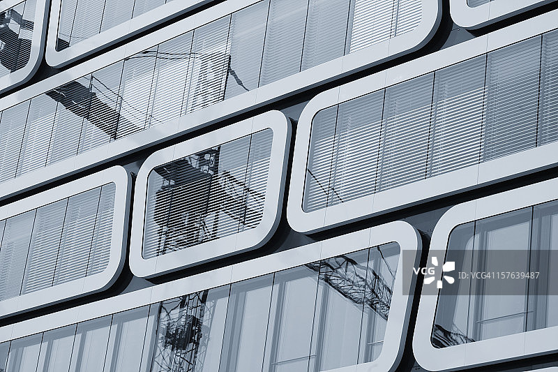现代办公楼的窗户反射着起重机的影像图片素材
