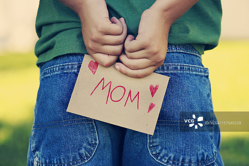 小孩在背后藏给妈妈的纸条图片素材