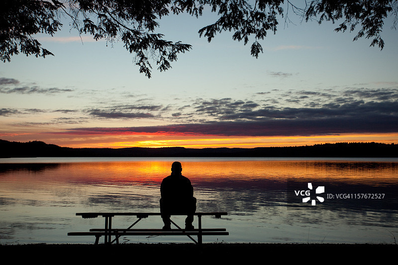 孤独的男人在湖边看日落图片素材