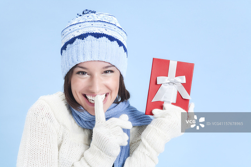 穿着毛衣，手拿红色礼品盒的年轻女子图片素材