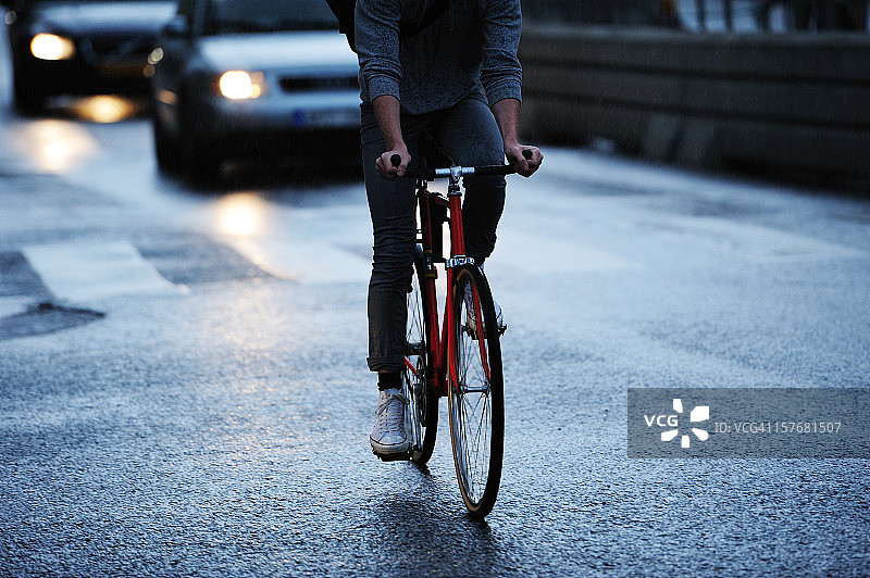 年轻人在城市里骑自行车，雨夜交通图片素材