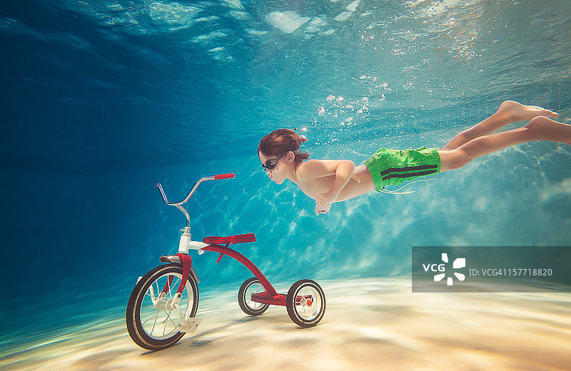 男孩在水下伸手去拿三轮车图片素材