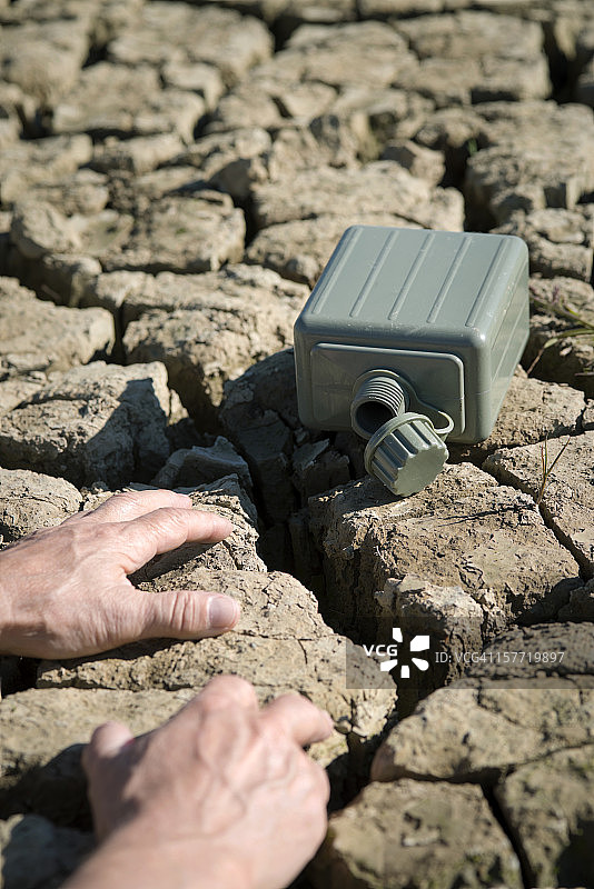 干燥地面上的手和空军用水容器图片素材