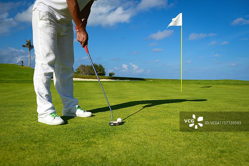在绿色高尔夫球场上推杆的男高尔夫球手图片素材