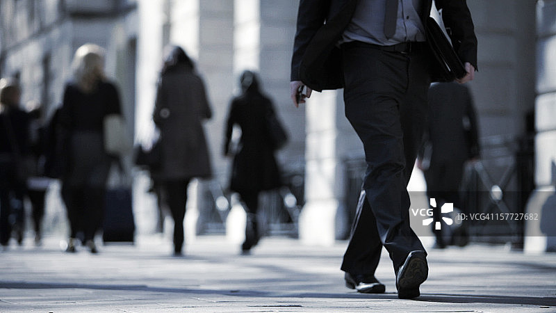 西装革履的男人走在繁华街道上的特写图片素材