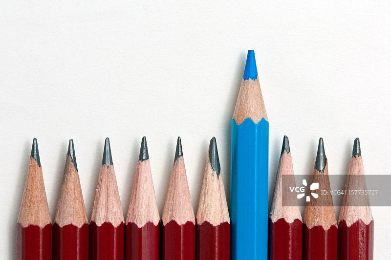 一排红色铅笔中突出的蓝色铅笔图片素材