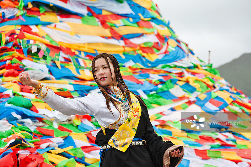 在祈祷旗前祈祷的藏族女孩图片素材