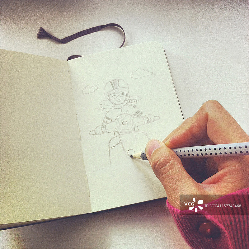 艺术家用铅笔在素描本上绘制女孩和滑板车图片素材