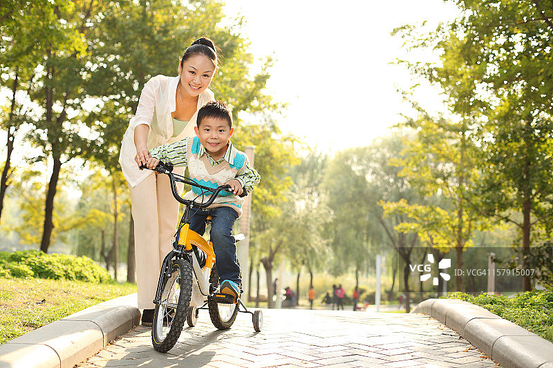妈妈教儿子在公园里骑自行车图片素材
