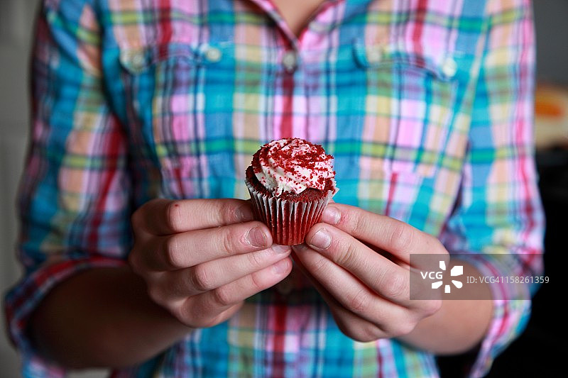 女孩拿着迷你红色天鹅绒纸杯蛋糕图片素材