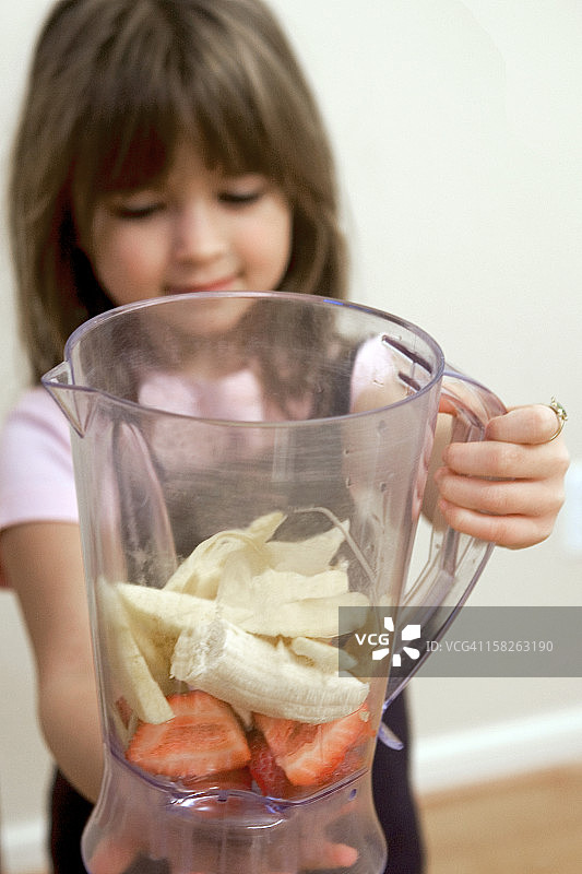 女孩将水果放入搅拌机图片素材