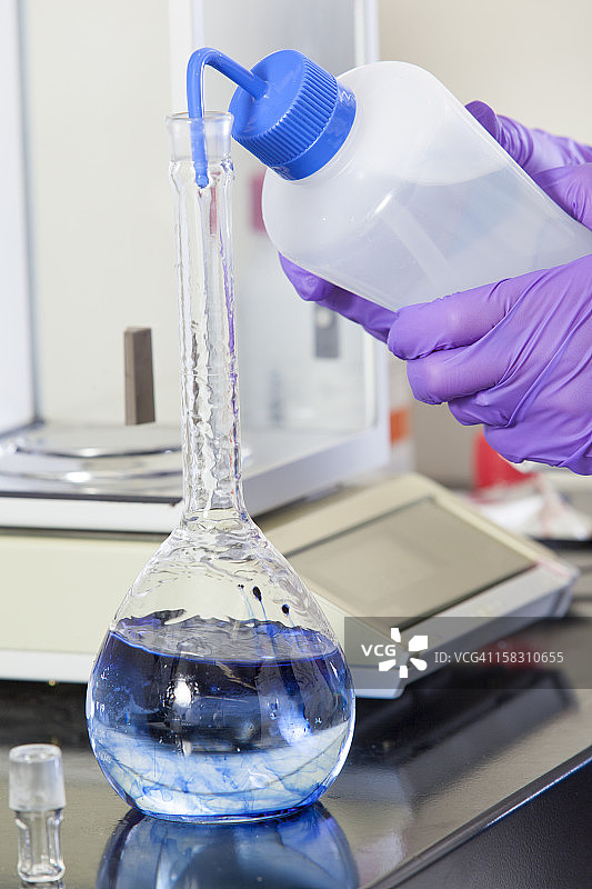 实验室科学家将靛蓝洗入水样本瓶中图片素材