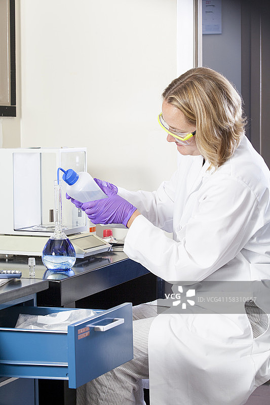 实验室科学家将靛蓝洗入水样本瓶中图片素材