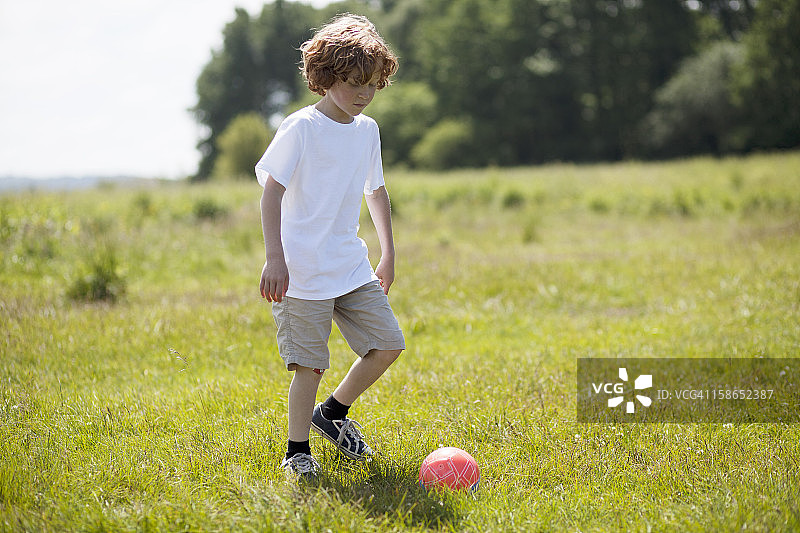 女孩在草地上踢足球图片素材