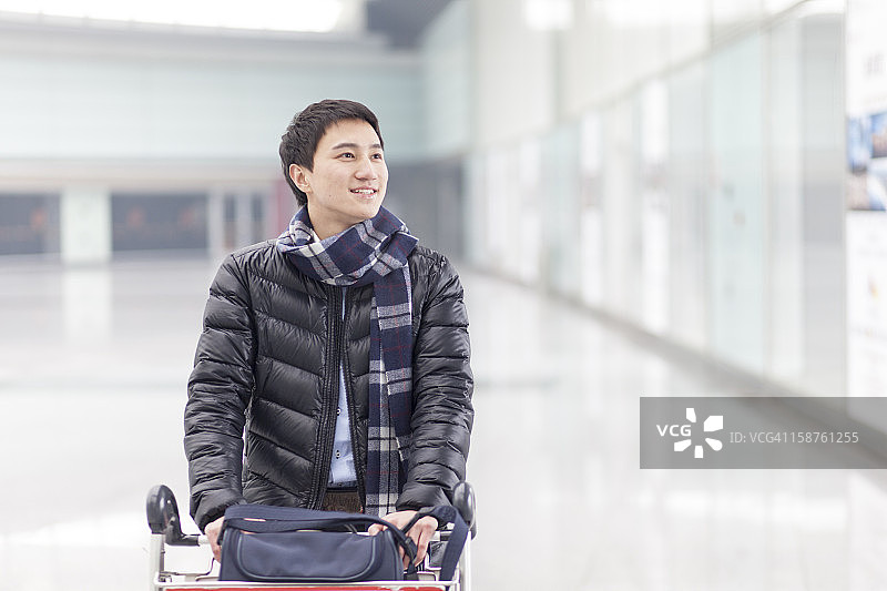 在机场拉着行李车的年轻男人图片素材