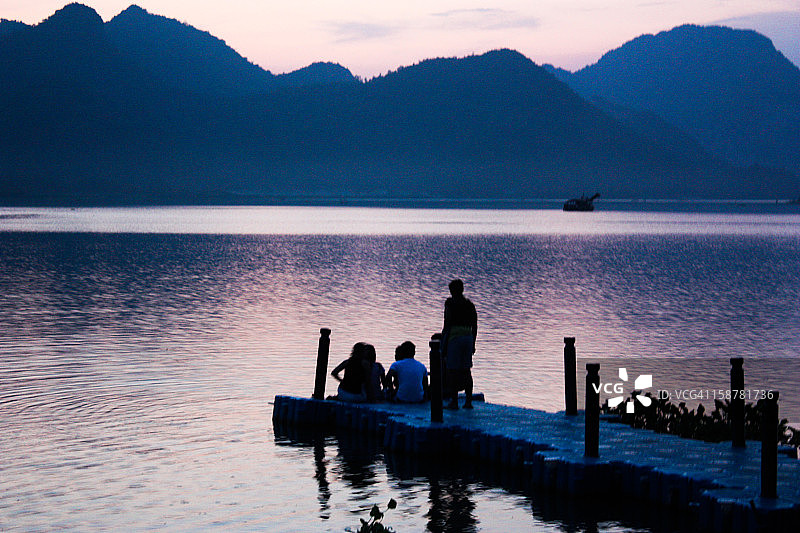 坐在日落时分的河边码头上图片素材