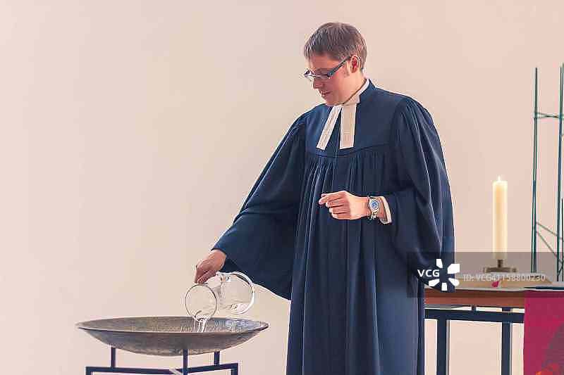 牧师在碗里倒洗礼用水图片素材