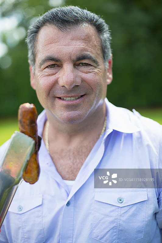 微笑的男人在户外烤热狗图片素材