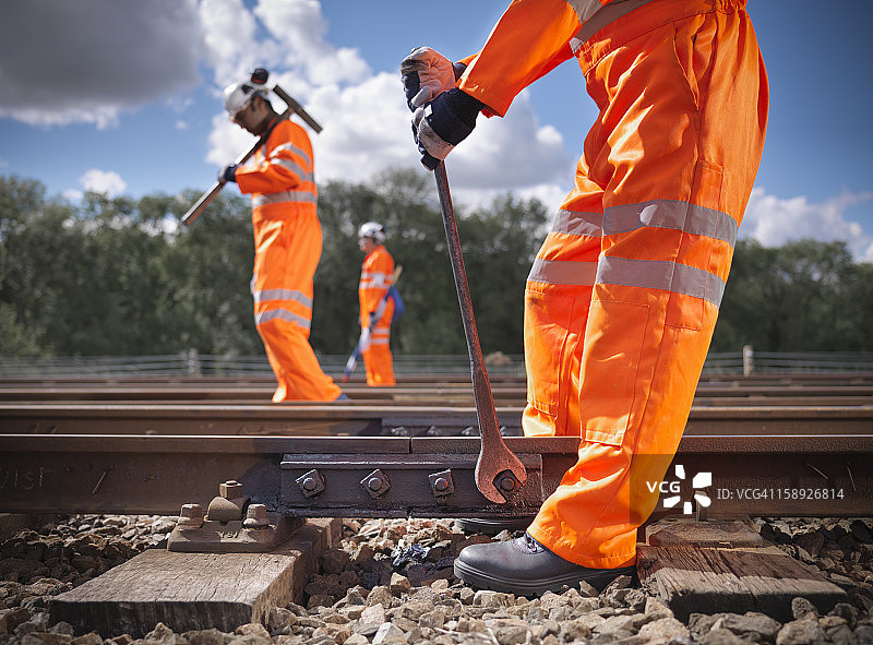 身穿高可视度服装的铁路工人正在维修铁轨图片素材