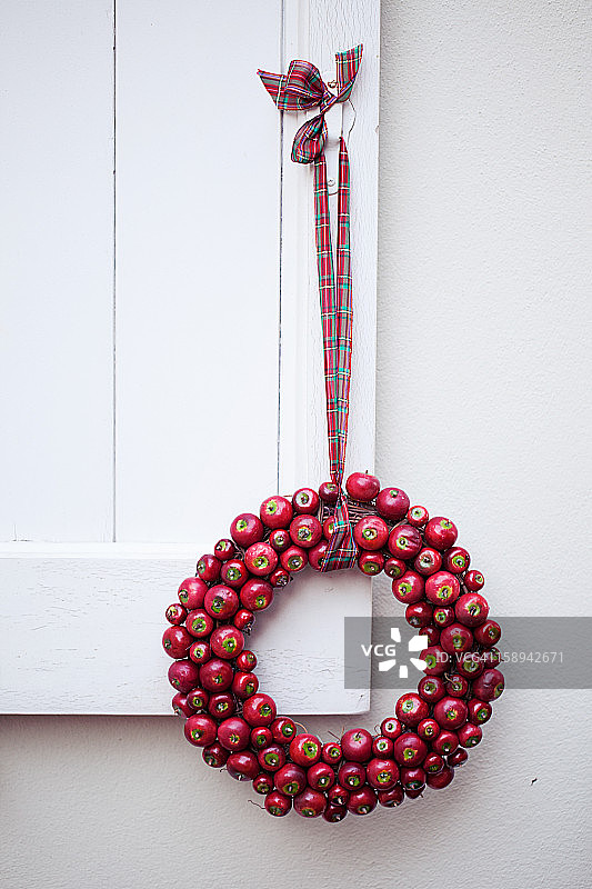 木窗户上悬挂的红苹果花环图片素材