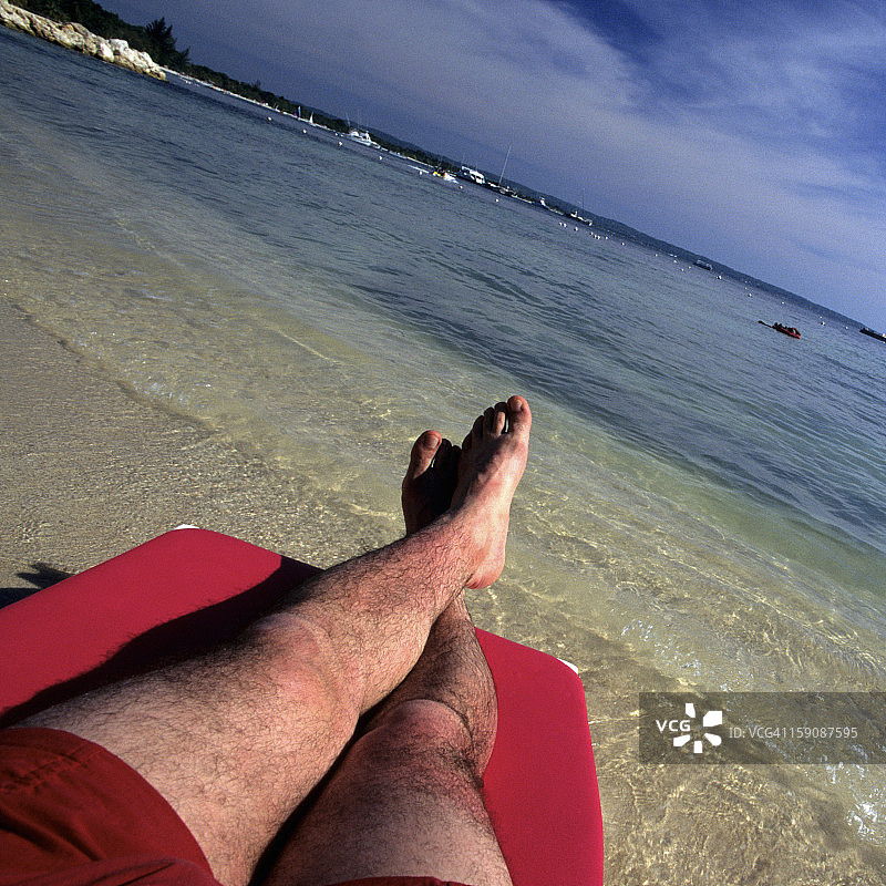 男子在牙买加海滩的躺椅上放松图片素材