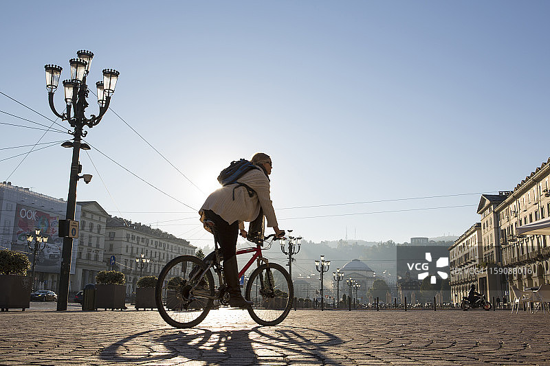 女人在城市广场骑自行车，日出图片素材