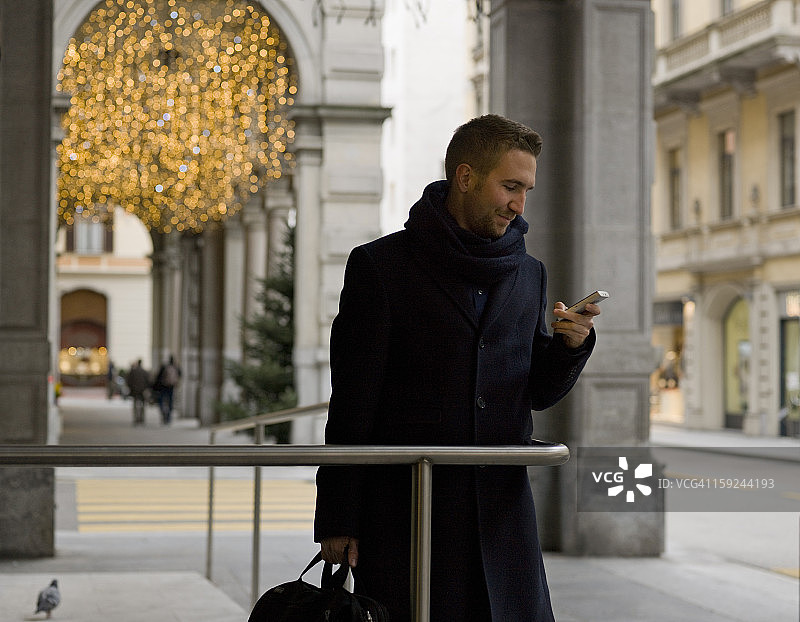 圣诞节期间，商人在门廊下查看手机图片素材