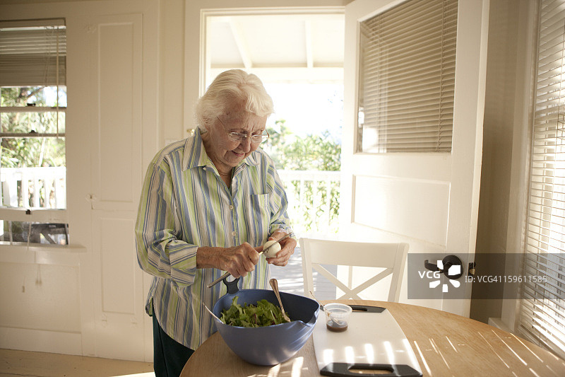 年长的女人在准备沙拉图片素材