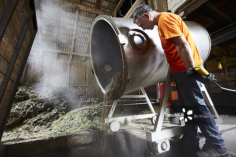 工人在车间倾倒桶中混合物图片素材