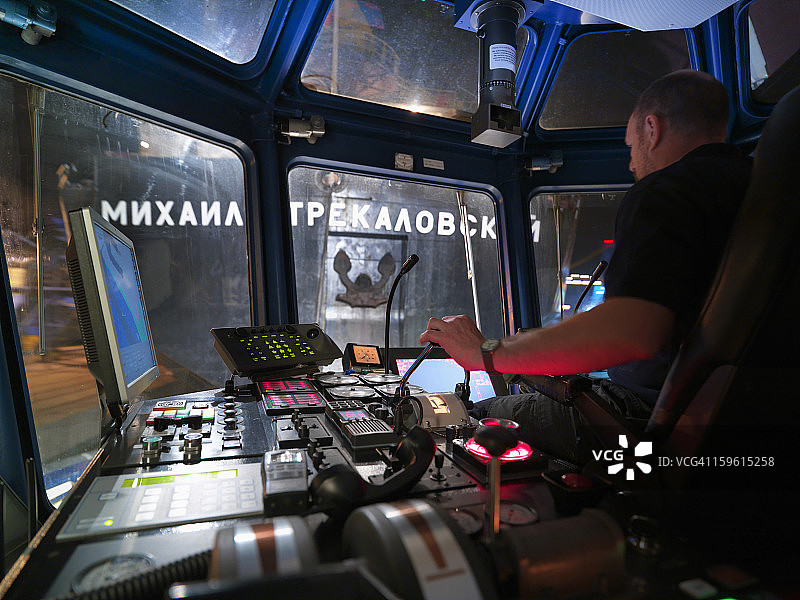拖船船长在驾驶室，透过窗户可以看到俄罗斯“MIKHAIL STREKELOVSKIY”号船尾图片素材