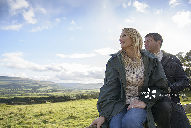 情侣坐在栅栏上欣赏温斯利代尔乡村风光图片素材