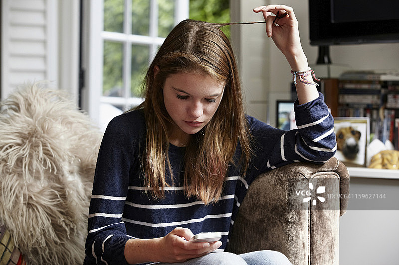 看着手机玩头发的青少年图片素材