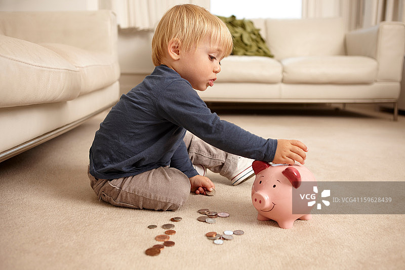 男孩把硬币放进存钱罐图片素材
